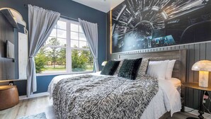A bedroom with a large bed, a window with curtains, a wall-mounted TV, and a ceiling light. - A Galaxy?s Edge Experience Awaits! 5 Min to Disney (Kissimmee)