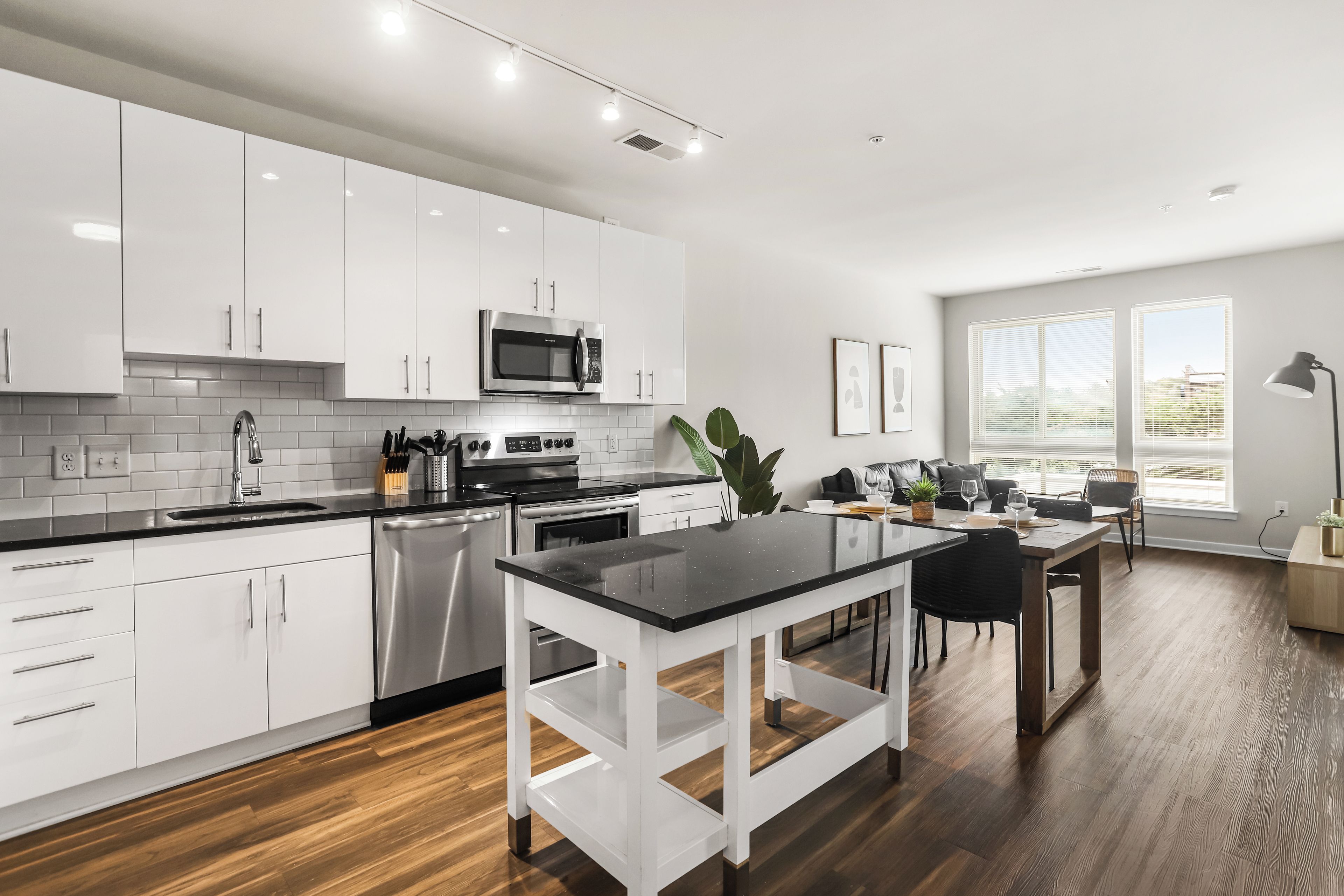 Una cocina moderna con muebles blancos, electrodomésticos de acero inoxidable y encimera negra.