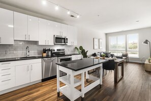 A modern kitchen with white cabinetry, stainless steel appliances, and a black countertop. - Huntington Apartments near Huntington Metro - We Host (Alexandria)