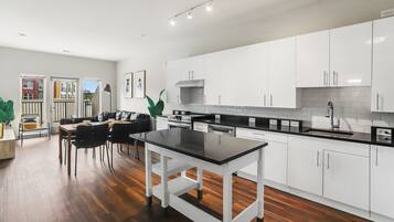 A modern kitchen with white cabinets, a black countertop, and a dining area with a table and chairs.