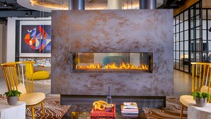 A modern lounge area with a central fireplace, seating, and a large abstract painting on the wall. - Huntington Apartments near Huntington Metro - We Host (Alexandria)