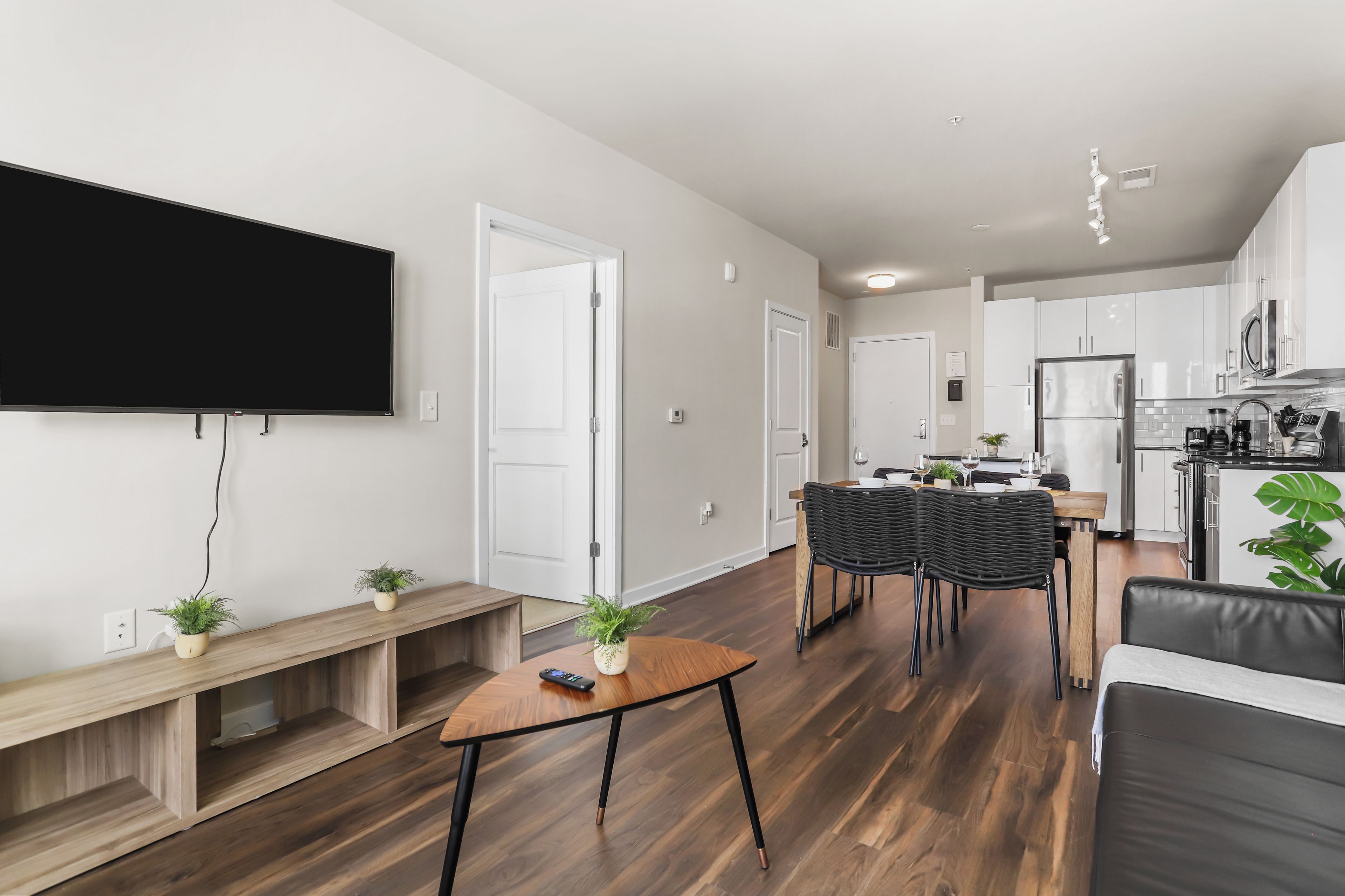 Una sala de estar moderna con televisor de pantalla plana, un banco de madera y un comedor con mesa y sillas.