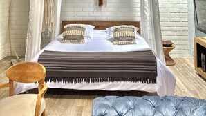 A bed with a canopy, a wooden ceiling, a woven hanging light fixture, and a macramé wall hanging.