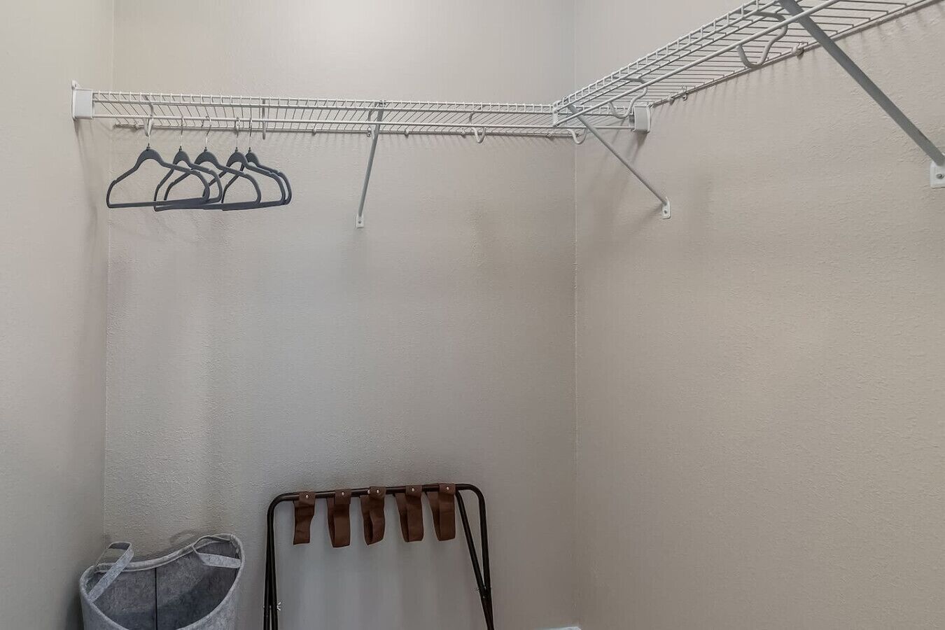 Un área de lavandería con un tendedero metálico, un secador de ropa y un cesto gris para ropa.