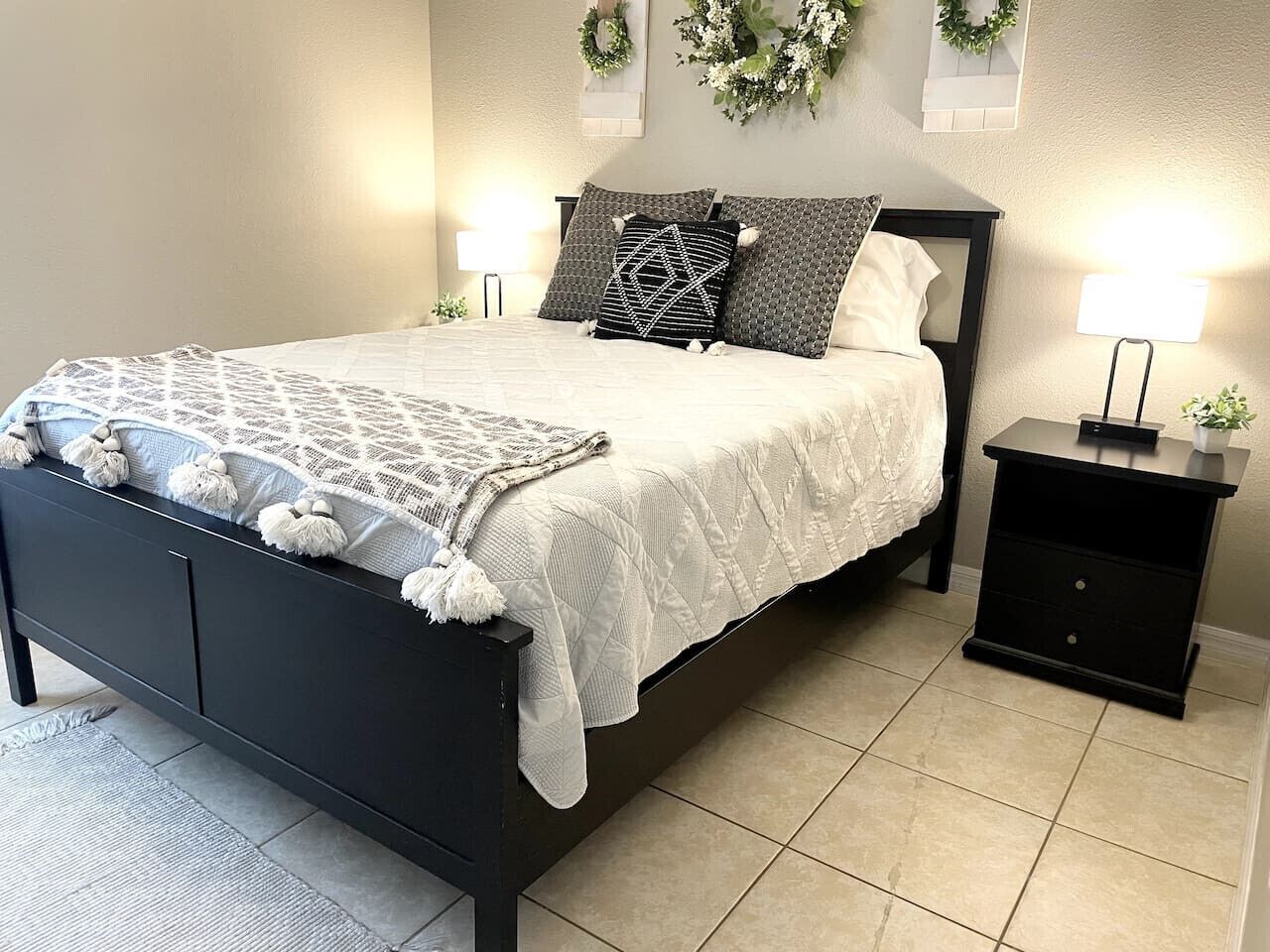 A bedroom with a bed, nightstands, and wall-mounted lights.