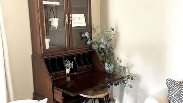 A living room with a dark wooden cabinet, a small stool, and two chairs.