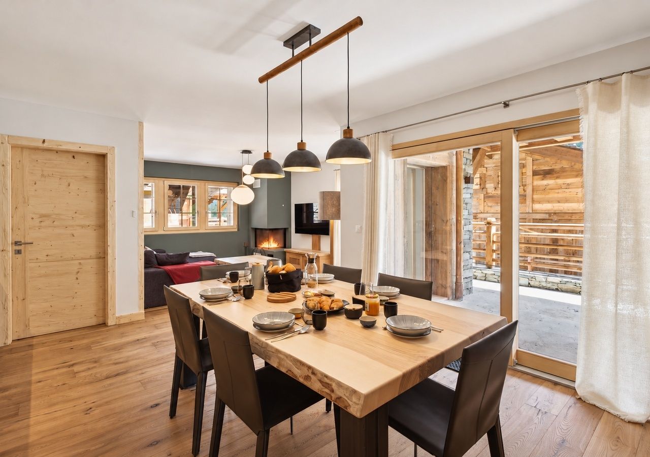 Ein Essbereich mit einem Holztisch, der für eine Mahlzeit gedeckt ist, umgeben von Stühlen.