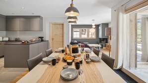 Una cocina moderna con armarios grises, una isla de madera y un comedor con una mesa larga dispuesta para una comida.
