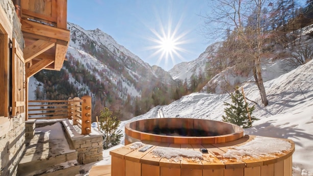 Una bañera de madera caliente en una zona montañosa nevada con cielo despejado.