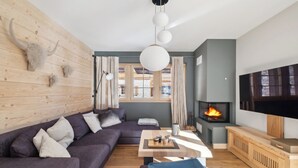 Una sala de estar moderna con una pared de madera, un sofá grande, una mesa de centro, una chimenea y un televisor.