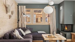 Una sala de estar acogedora con una pared de madera, un sofá, una mesa con una bandeja de tazas y una chimenea.