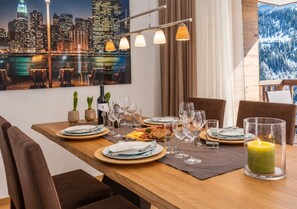 A dining table set with plates, cutlery, and glasses, with a cityscape view and a candle on the table.