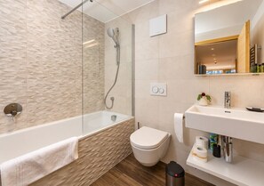 A modern bathroom with a glass-enclosed shower, a white toilet, and a vanity with a mirror.