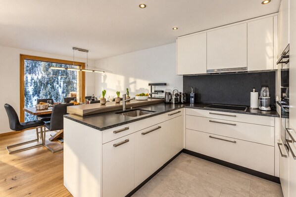 A modern kitchen with white cabinetry, a black countertop, and stainless steel appliances.
