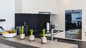 A modern kitchen with white cabinets, a black backsplash, stainless steel appliances, and a fruit bowl with apples and bananas. - Luxury Apartment, 3 Bedrooms with Jacuzzi Chalet Rahas A Grimentz - By Mrs Miggins (Grimentz)
