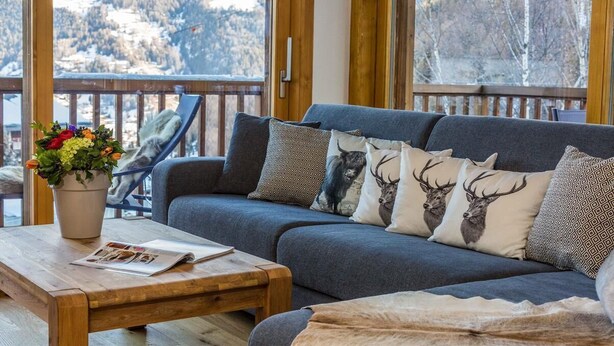 A cozy living area with a grey sofa, patterned cushions, a wooden coffee table, and a potted plant. - Luxury Apartment, 3 Bedrooms with Jacuzzi Chalet Rahas A Grimentz - By Mrs Miggins (Grimentz)