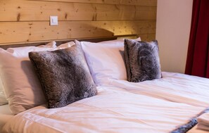 Una cama con sábanas blancas y dos almohadas grandes de color gris oscuro.