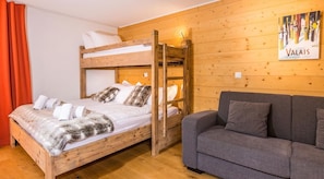 Um quarto com uma cama beliche, um sofá, paredes de madeira e um quadro.