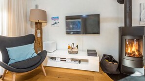 Ett modernt vardagsrum med en soffa, en platt-TV, en öppen spis och en vit möbel för underhållningsutrustning.