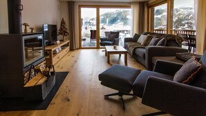 Ein gemütliches Wohnzimmer mit Kamin, einer Couch, einem Couchtisch und einem Fernseher.
