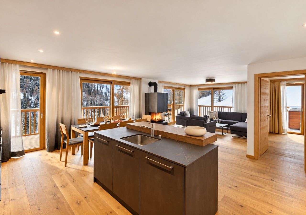 A spacious living area with a large island kitchen, wooden flooring, and a fireplace.