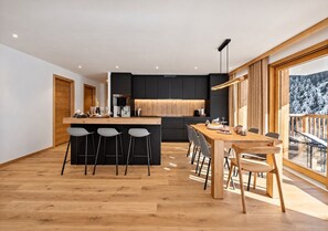 A modern kitchen with a central island, bar stools, and a dining table with chairs.