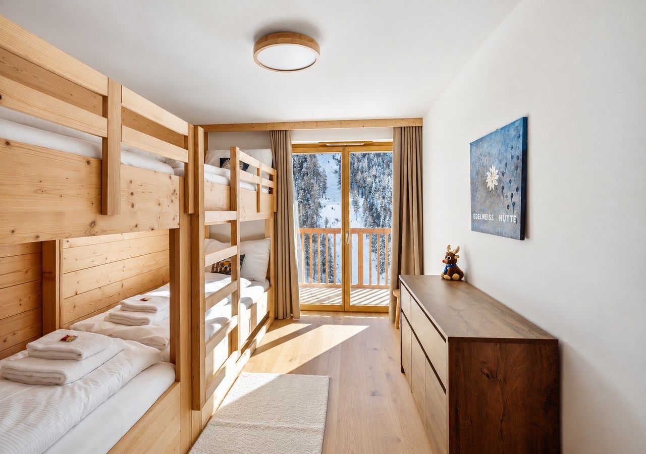 Ein Zimmer mit einem Holzbett mit Etagen und einer Schiebetür, die auf einen Balkon führt.