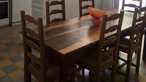A kitchen with a wooden dining table, chairs, a red pendant light, and a window with a view of greenery. - Maison de Village, en Provence Dans Triangle Avignon-arlesnîmes (Vallabrègues)