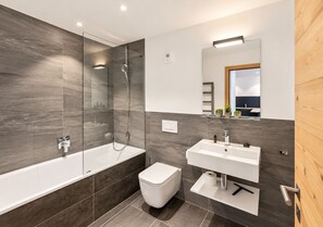 Ein modernes Badezimmer mit einer Badewanne, Toilette und Waschbecken.