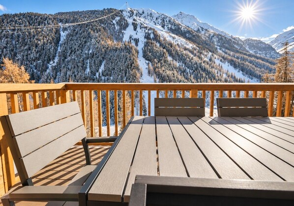 A wooden deck with benches overlooking a snowy mountain landscape.