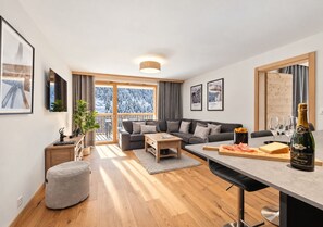Ett modernt vardagsrum med en soffa, ett soffbord och en matplats med ett bord dukat för en måltid.