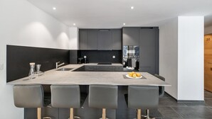 Una cocina moderna con una isla central, taburetes de bar y un refrigerador.