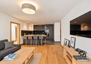 Ett modernt vardagsrum med en soffa, ett soffbord och ett köksområde i bakgrunden.