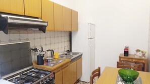 Una cocina compacta con armarios de madera, una estufa a gas, un lavamanos y un refrigerador.