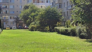 A residential area with multi-story buildings, a grassy lawn, and parked cars. - Family Heritage from past to the future (Sibiu)