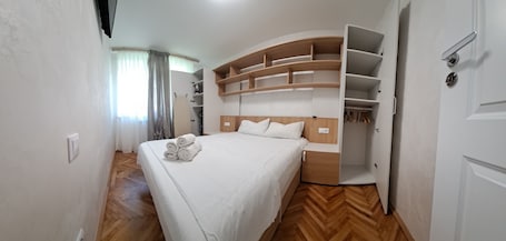 A bedroom with a bed, a built-in wardrobe, and a wooden floor.