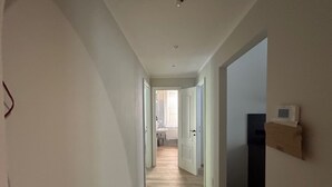 A narrow hallway with a wooden floor leading to a bathroom with a sink and mirror. - Oleandri cosy Apartment Near best beaches (Monterosso al Mare)