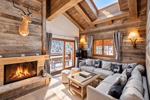 A cozy log cabin interior with a fireplace, a sofa set, and a television.