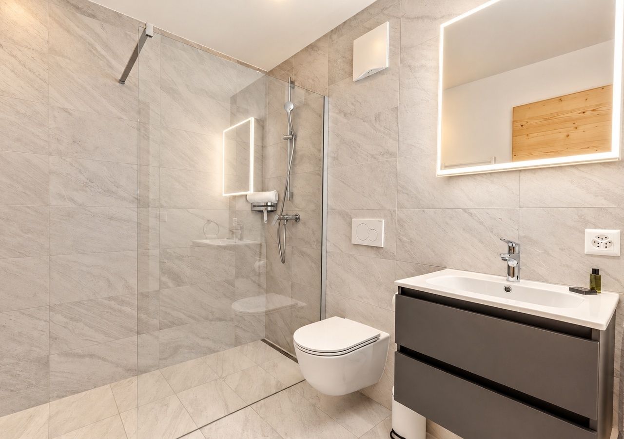 A modern bathroom with a glass-enclosed shower, a toilet, and a vanity with a sink.
