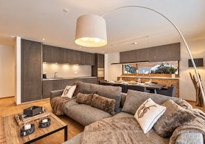 A modern living room with a sectional sofa, a coffee table, and a dining area in the background.