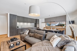 Uma sala de estar moderna com um conjunto de sofá, uma mesa de centro e um espaço de jantar com vista para uma paisagem nevada.