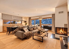 Una sala de estar moderna con chimenea, comedor y vistas a un paisaje nevado.