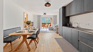 Une cuisine moderne avec un coin repas, un plancher en bois et une vue sur l’extérieur.