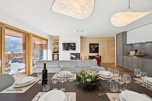 Uma sala de jantar moderna com uma mesa grande posta para refeição, uma garrafa de vinho e um arranjo decorativo.