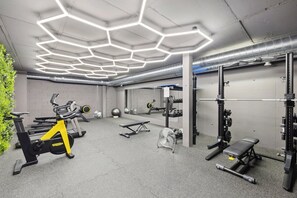 A modern gym with hexagonal ceiling lights, exercise equipment, and a mirrored wall.