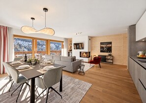 A modern living space with a dining area, a sofa, a fireplace, and a kitchen.