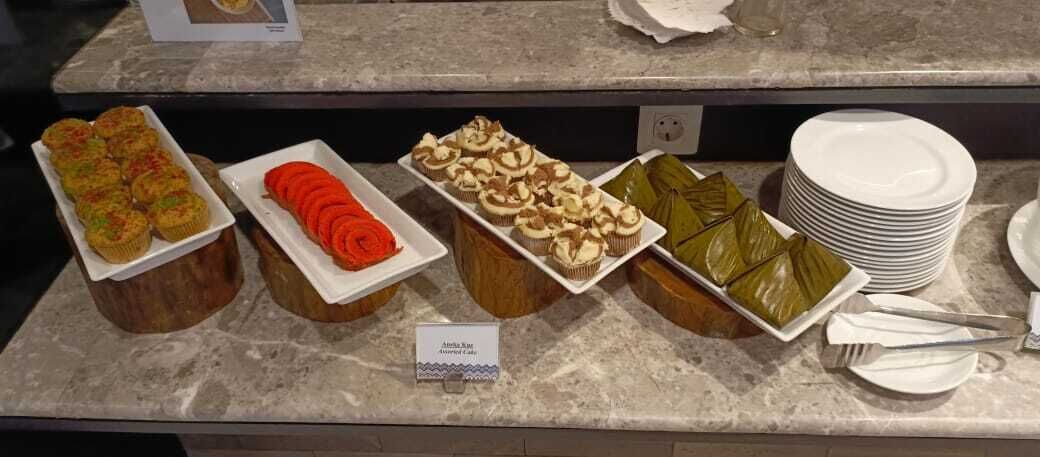 Ein Buffet mit verschiedenen Speisen, darunter ein Gericht mit rotem Gemüse, eine weiße Speise mit grüner Dekoration und eine Speise mit brauner Auflage.