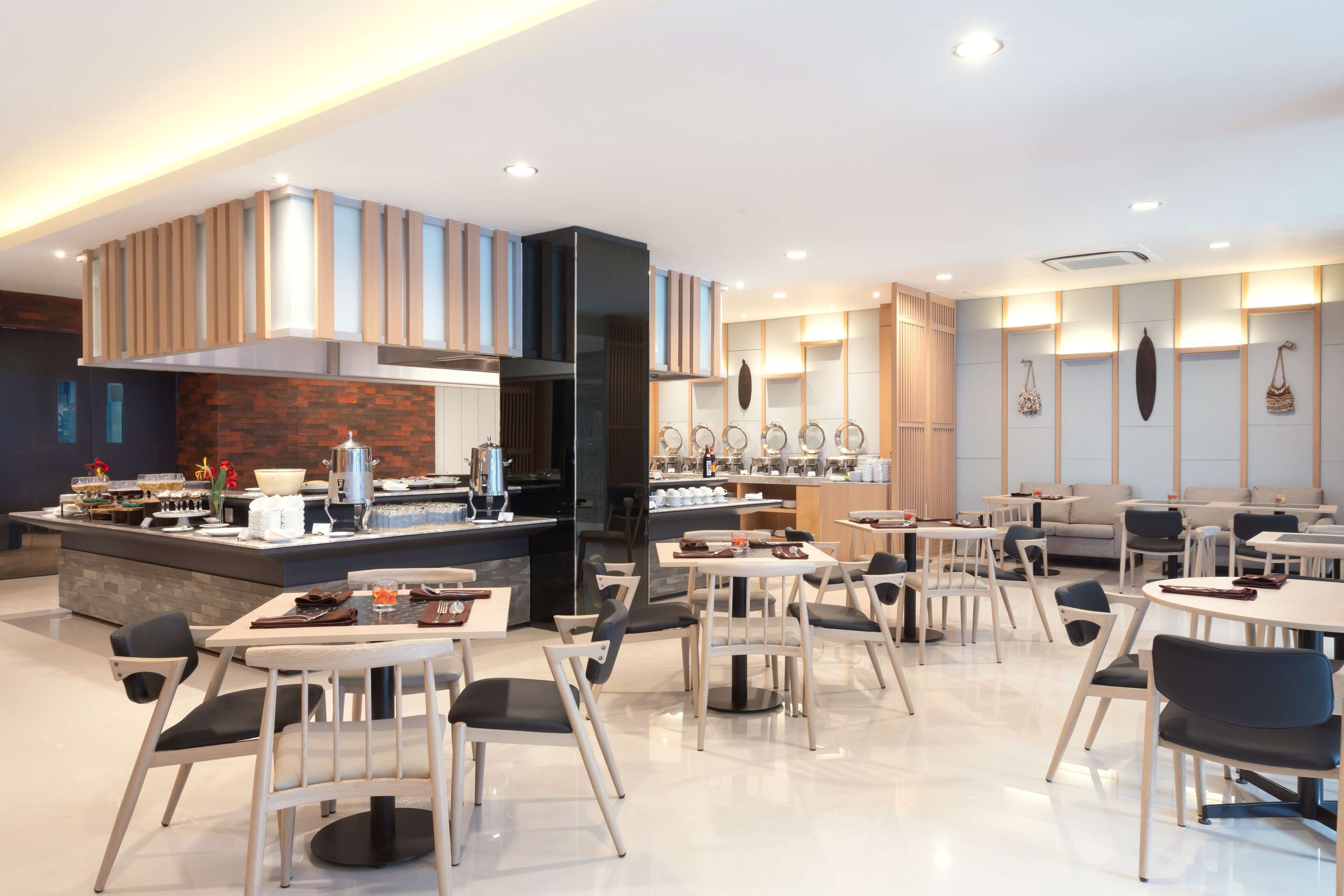Un restaurant moderne doté d’un bar central, de nombreuses tables et de différents types de sièges.