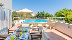 A rooftop terrace with a pool, sun loungers, and a dining table set for breakfast. - Villa Filia in Prines (Rethymno)