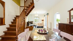 A spacious dining area with a wooden staircase leading to a living room. - Villa Filia in Prines (Rethymno)